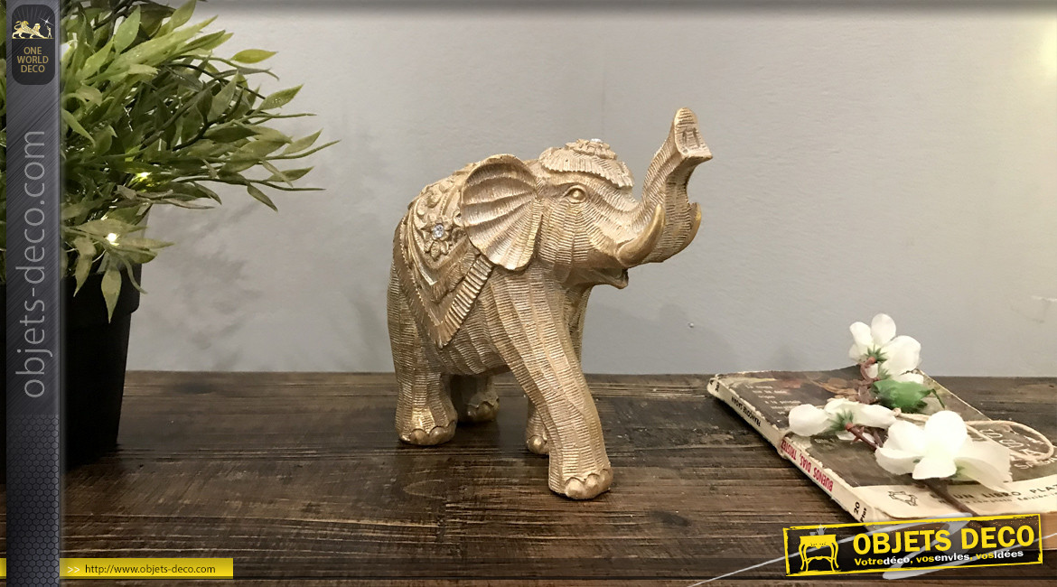 Statuette d'un éléphant en résine effet bois sculpté, reflets dorés sur fond brossé, 17cm