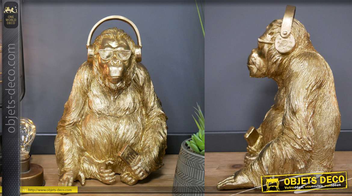 Représentation d'un gorille en résine, avec casque audio sur les oreilles, finition doré brillant, 35cm de haut