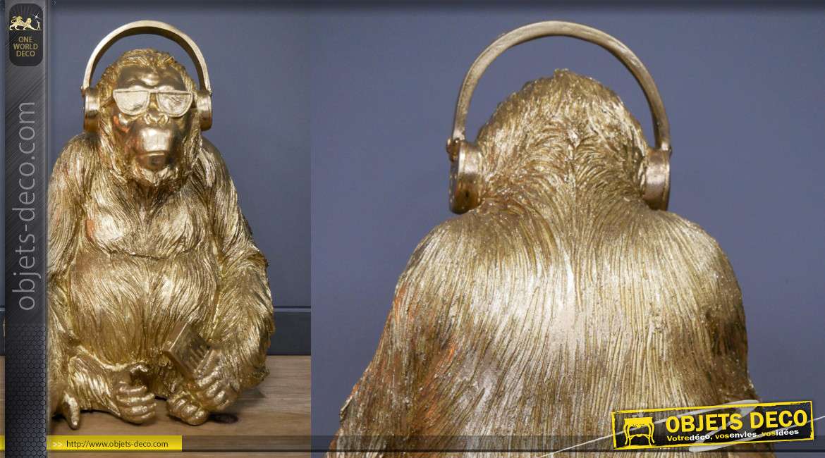 Représentation d'un gorille en résine, avec casque audio sur les oreilles, finition doré brillant, 35cm de haut