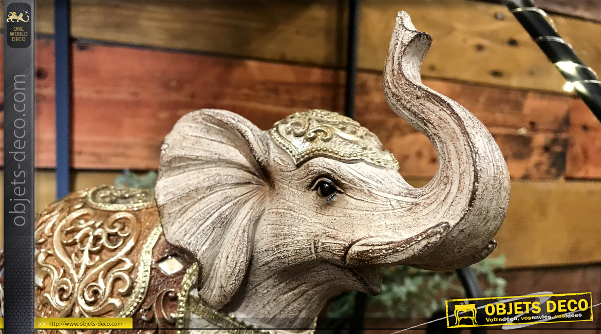 Représentation d'un éléphant avec habit oriental, finition dorée et facettes miroitées, en résine effet bois sculpté, 24cm