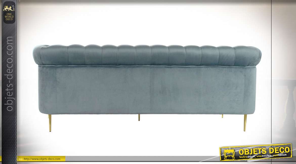 Grand canapé trois places capitonné style rétro finition velours bleu, série de deux coussins carrés fausse fourrure blanche, 230cm