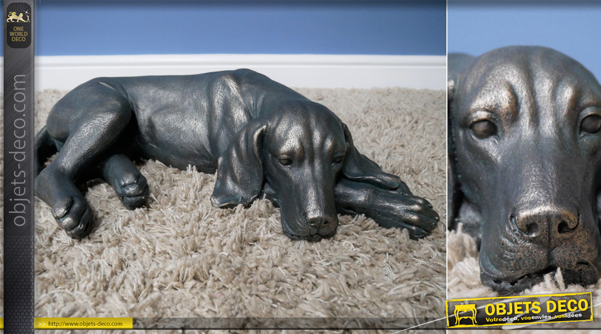 Représentation d'un chien allongé en résine finition noir charbon et reflets bronze, ambiance campagne, 58cm