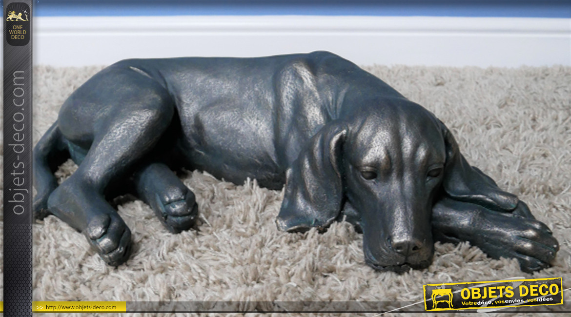 Représentation d'un chien allongé en résine finition noir charbon et reflets bronze, ambiance campagne, 58cm